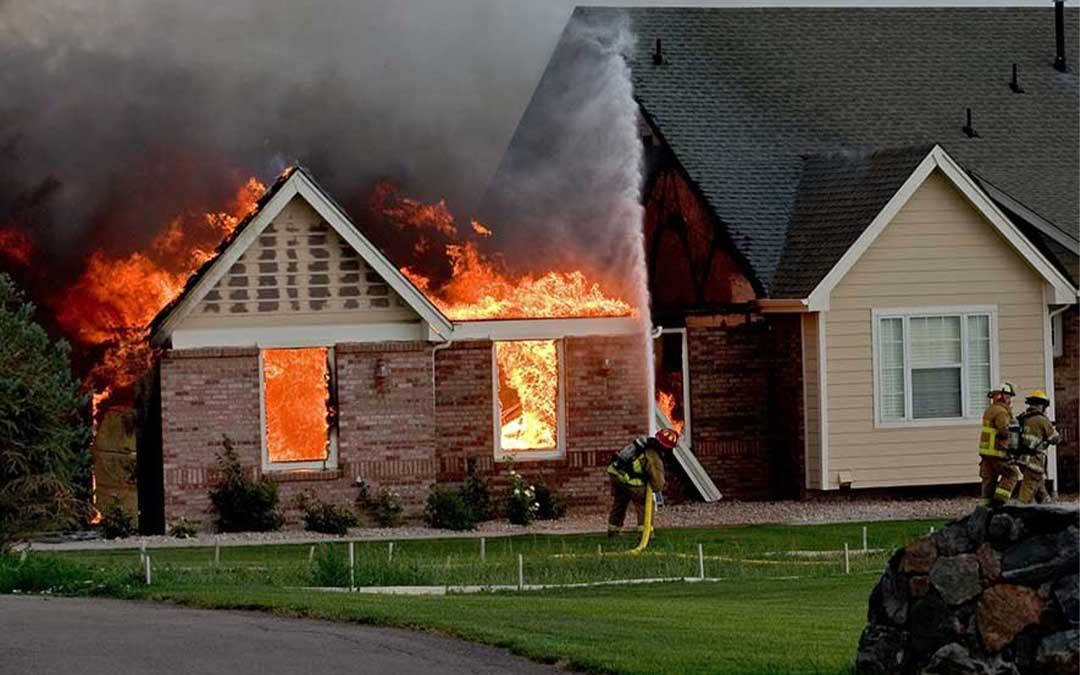 Fire fighters hosing down a house that's on fire