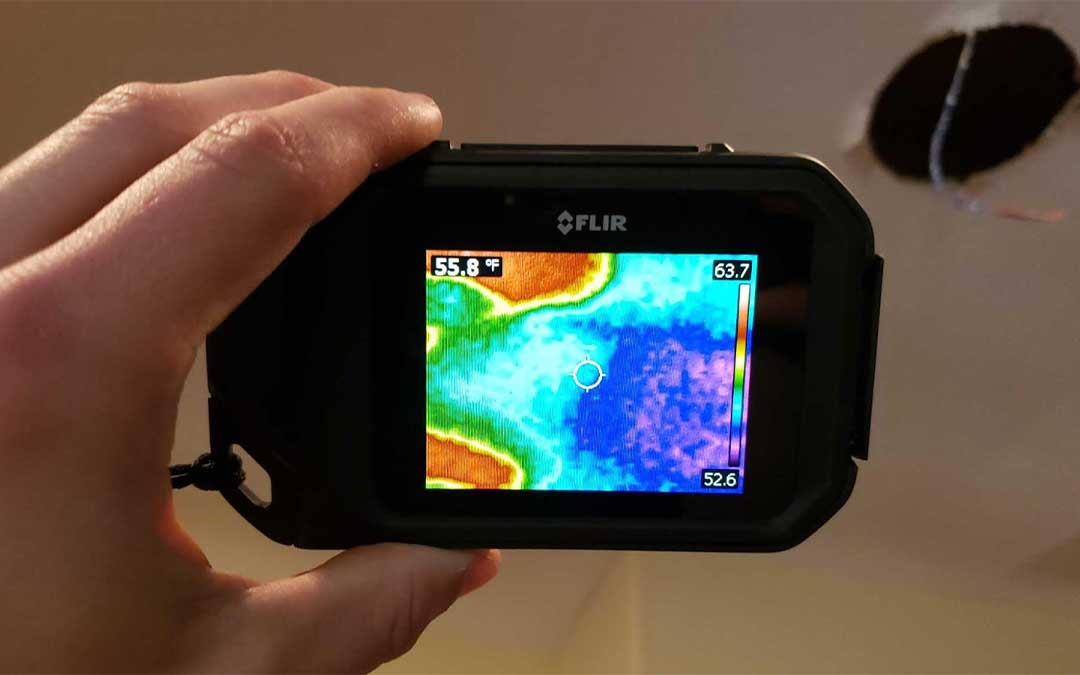 Water damage restoration expert scanning ceiling for mold
